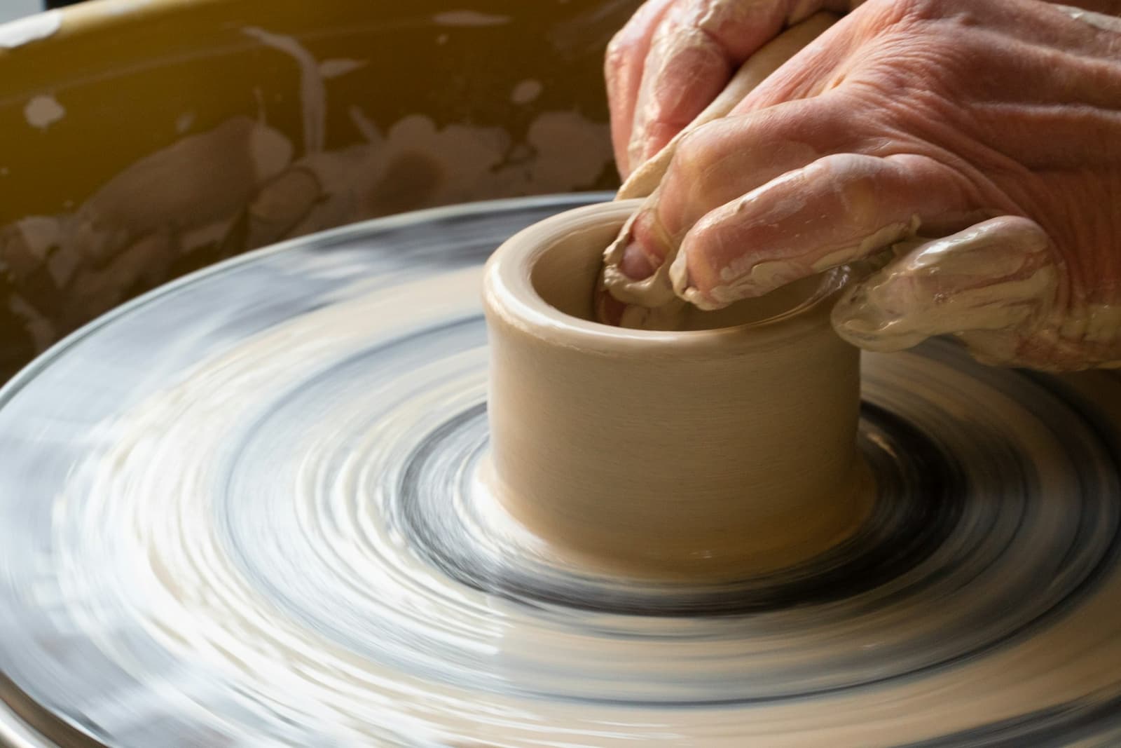 A person shaping a clay pot on a wheel