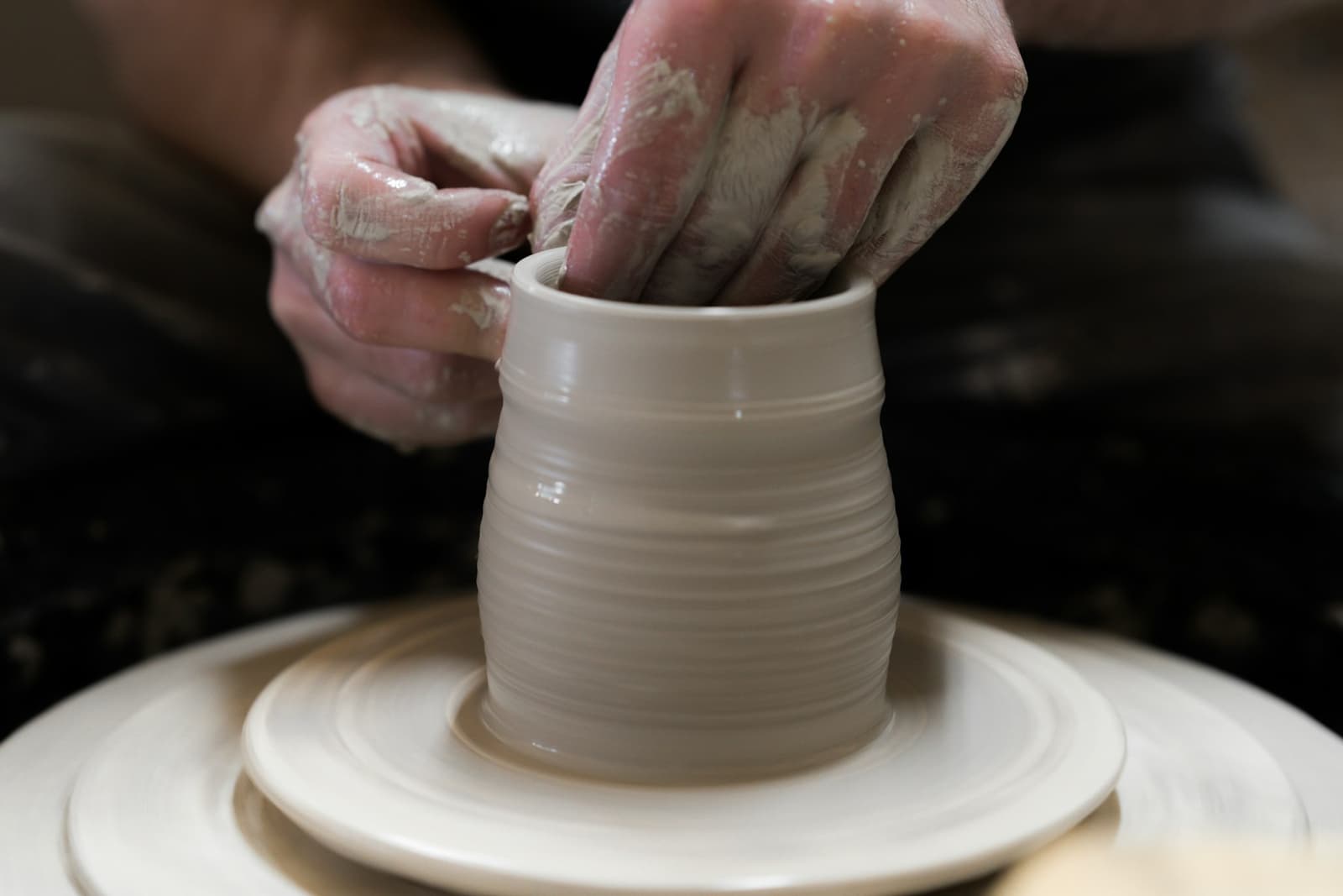 Hands shaping a pot on a wheel