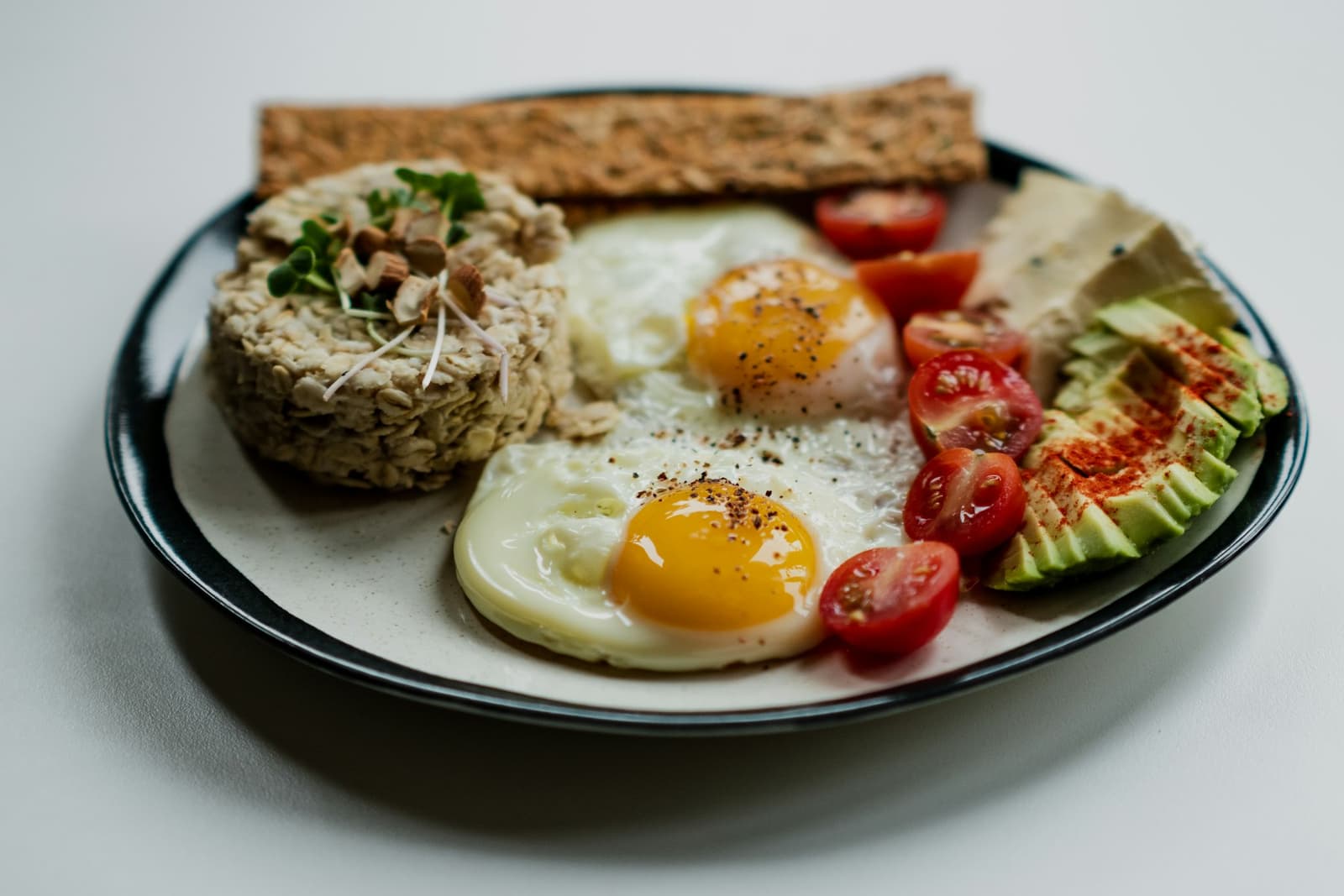Sliced bread topped with egg and vegetables on a white plate