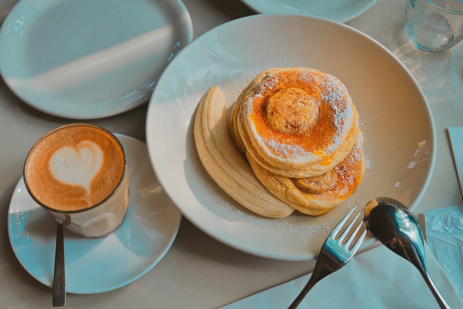 Pancakes with banana and a coffee with heart latte art