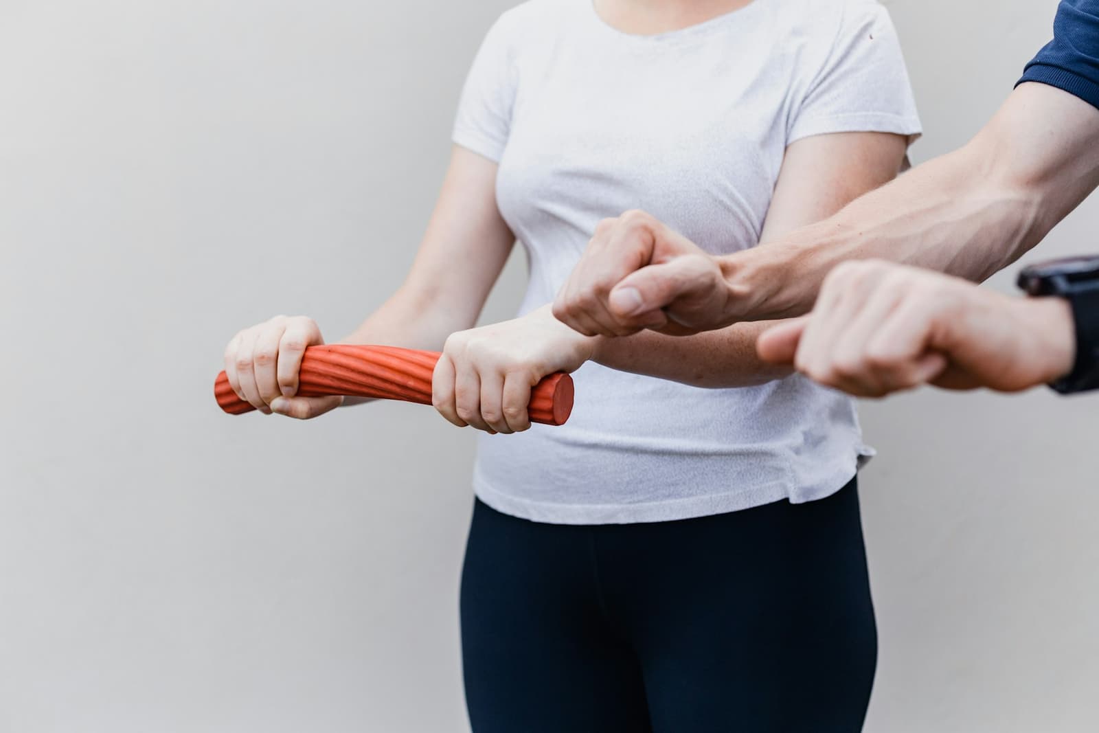 A woman holding a red handle while standing beside a man during an exercise session
