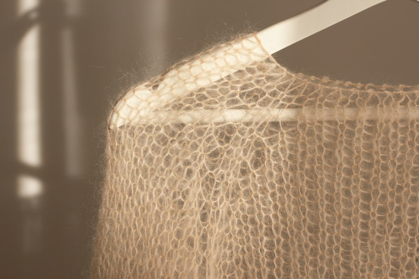 A soft knitted cardigan hanging on a white hanger