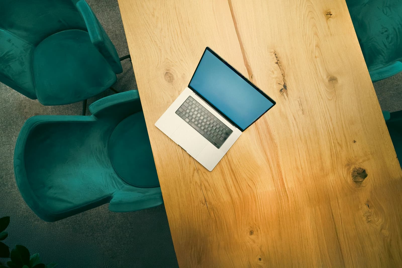 A laptop open on a wooden meeting table, seen from above